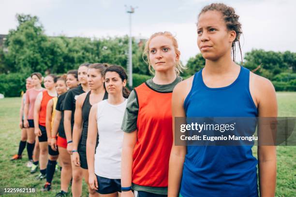 a line of women wearing sports vests in a training field during rugby training. - rugby boot stock pictures, royalty-free photos & images