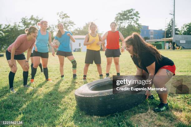 seven women at rugby training one lifting a tyre. - rugby boot stock pictures, royalty-free photos & images