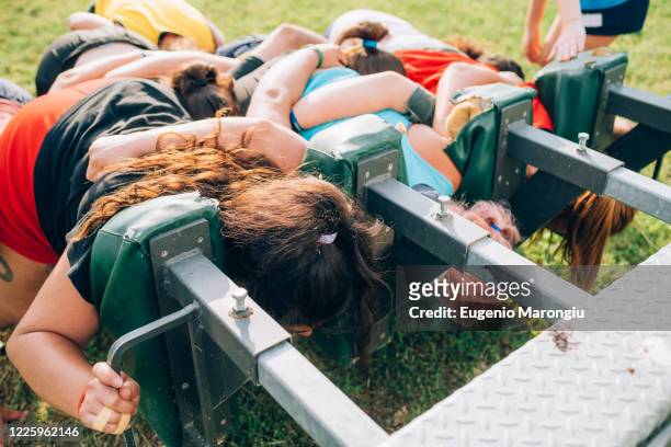 a group of women training to scrum against a machine on the training pitch. - rugby shorts stock-fotos und bilder