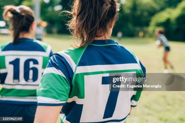 rear view of two women wearing blue, white and green rugby shirts on a training pitch. - sports jersey back stock pictures, royalty-free photos & images