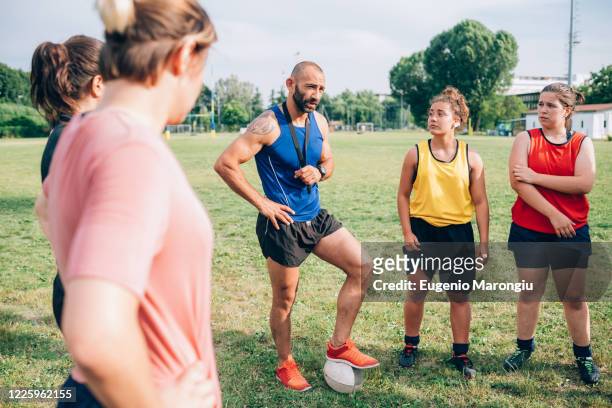 a group of women standing in a circle listening to their male rugby coach. - rugby boot stock pictures, royalty-free photos & images