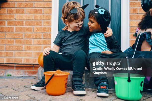 two children dressed for halloween with their arms around each others shoulders. - halloween kids stockfoto's en -beelden