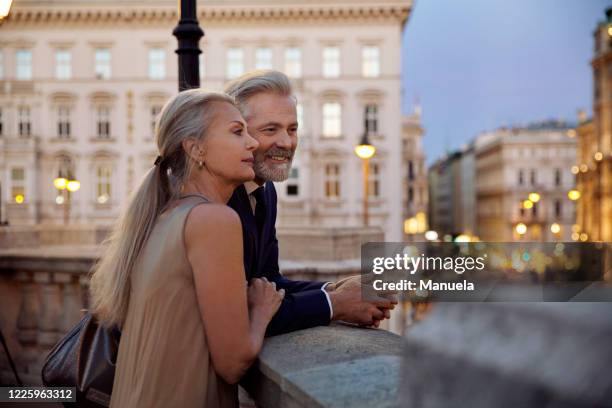 a couple leaning against a balustrade overlooking vienna during the evening. - austria city stock pictures, royalty-free photos & images