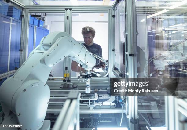 male trainee engineer with robotic equipment in unspecified. - roboterarm stock-fotos und bilder