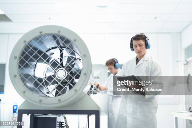two male scientists wearing white lab coats performing experiment in wind tunnel in unspecified. - industrial fan stock-fotos und bilder