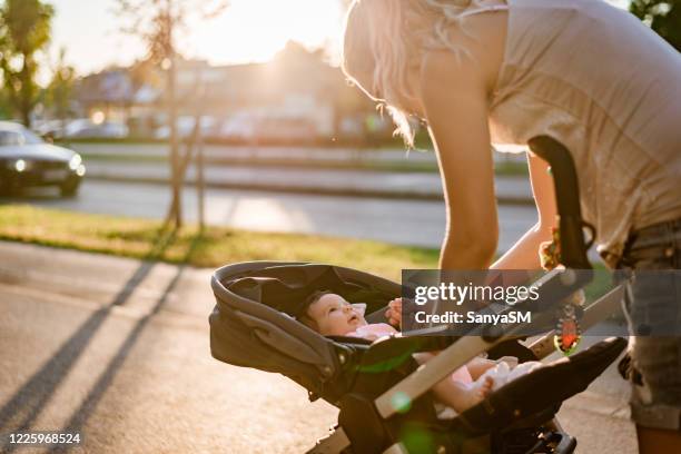 mère et nouveau-né sur le coucher du soleil - femme poussette rue photos et images de collection