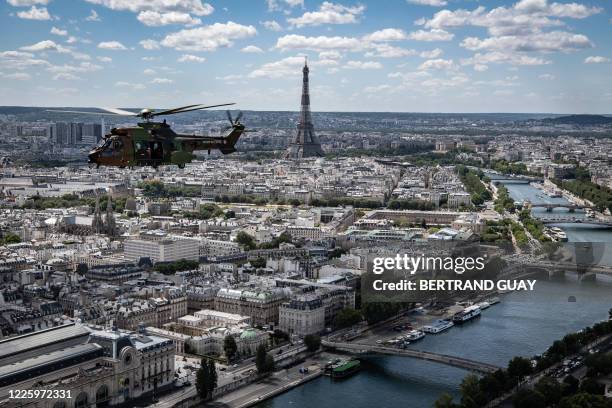 Cougar AS532 helicopter flies over the Eiffel Tower and the city of Paris on July 9, 2020 during a rehearsal ahead of a ceremony which will be held...