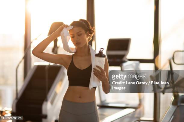 young chinese woman resting after exercising at gym - matt lane stock-fotos und bilder