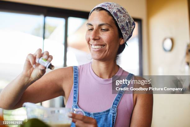 smiling woman mixing ingredients for her home-based organic cosmetics business - food additive stock pictures, royalty-free photos & images