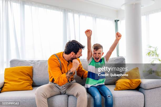 boy watching soccer match with father - cheering tv stock pictures, royalty-free photos & images