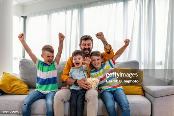 cheerful family cheering while watching sports match on tv at home - match 3 stock pictures, royalty-free photos & images