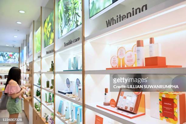 This picture taken on July 2, 2020 shows a woman browsing products by South Korean skincare brand Innisfree, which sells a range of whitening...