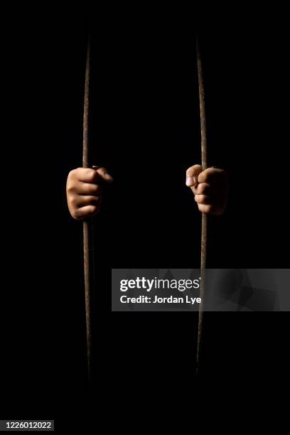 human hands bending rusty cage bars - security screen stockfoto's en -beelden