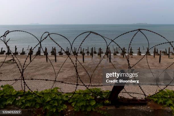 Metal spikes, known as "Dragon's teeth," and razor wire used for fortification sit along a beach as islands belonging to North Korea stand in the...