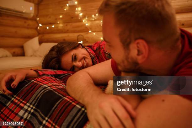 romantic couple enjoying their evening cuddles in bed - low lighting stock pictures, royalty-free photos & images