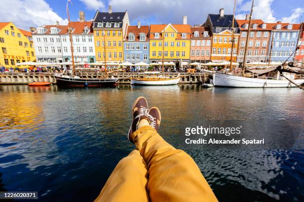 young man relaxing at nyhavn harbor in copenhagen, personal perspective view - pov shoes stock-fotos und bilder