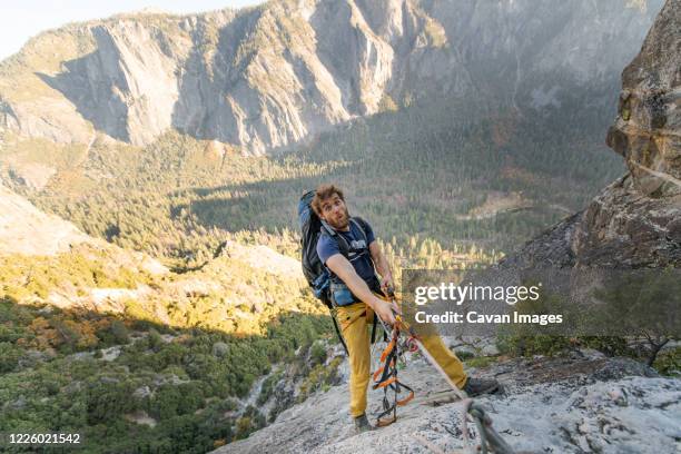 man jugging rope up on el capitan doing funny face with backpack - ascender stock pictures, royalty-free photos & images