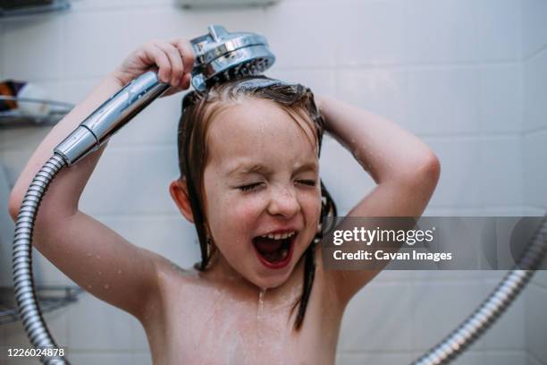 close up of young girl rinsing shampoo from hair in shower - kids taking a shower stockfoto's en -beelden