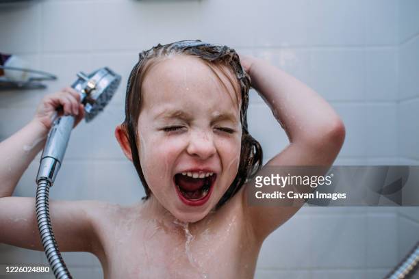 close up of young child singing in shower while washing hair - singing shower stock pictures, royalty-free photos & images