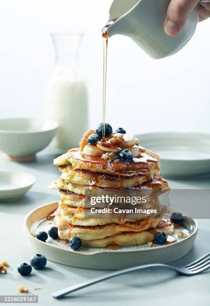stack of blueberry banana walnut pancakes with syrup pouring breakfast - pancakes stock-fotos und bilder