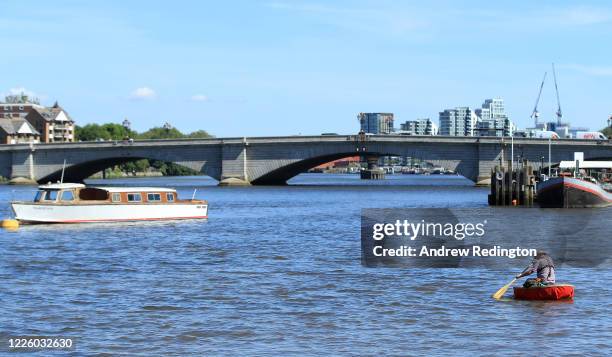 General view as a man paddles a coracle towards Putney Bridge on May 20, 2020 in London, England. The British government has started easing the...