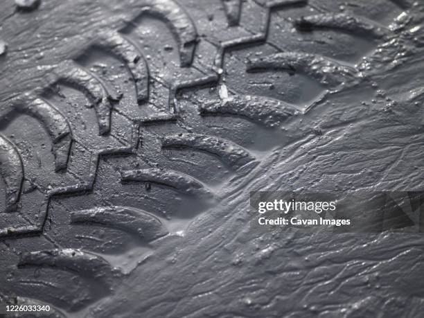 close up of suv tyre tracks in grey mud - tyre track stock pictures, royalty-free photos & images