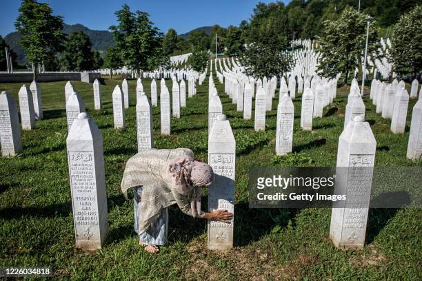 Bosnian Muslim woman cleans a gravestone of her relative, a victim of Srebrenica genocide, July 10 at the cemetery in Potocari near Srebrenica,...