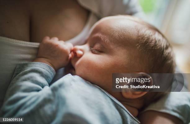 la madre allatta e gioca con il suo neonato - seno foto e immagini stock