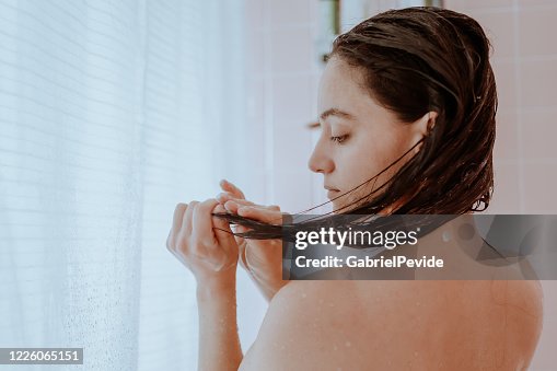 Mujer tomando una ducha y lavándose el pelo en casa Mujer tomando una ducha y lavándose el pelo en casa