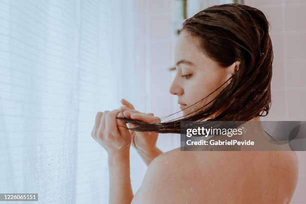 vrouw die een douche neemt en haar haar thuis wast - shampoo stockfoto's en -beelden