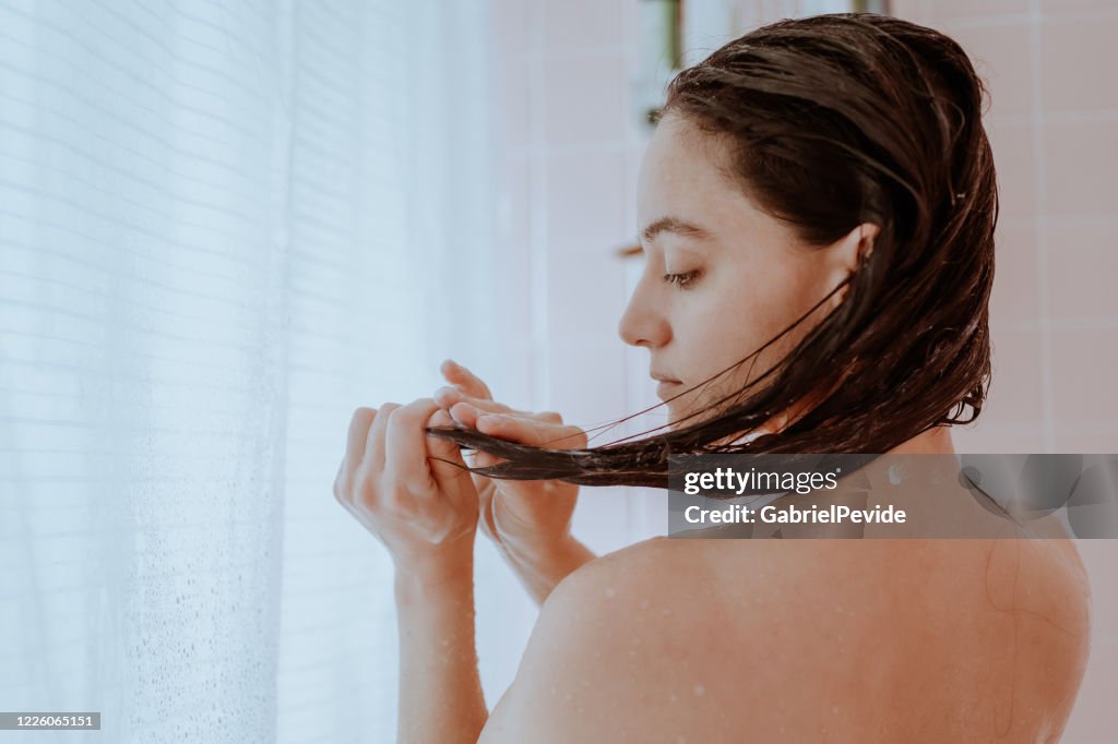 Mulher tomando banho e lavando o cabelo em casa