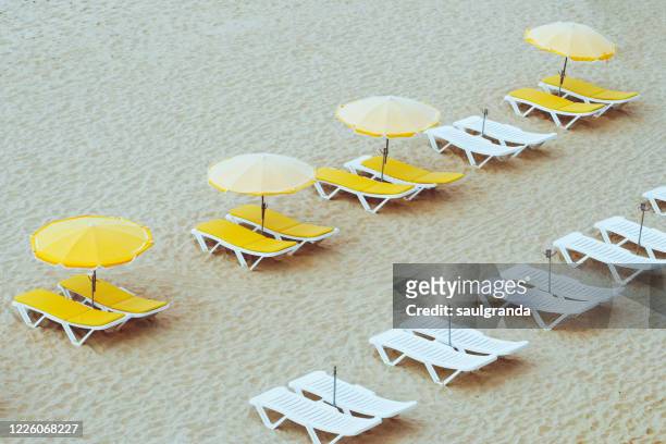 beach umbrellas and loungers on an empty beach - strand liegen stock-fotos und bilder