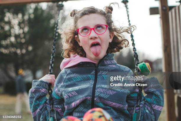 girl swinging and making a silly face - spoilt children stock-fotos und bilder