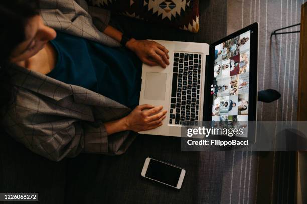 young woman using a laptop on the sofa at home to have a work conference call - live event business stock pictures, royalty-free photos & images