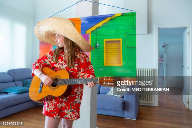 young girl pretending to be in vacations in mexico colorful village playing guitar in fake background - hat sombrero stock pictures, royalty-free photos & images