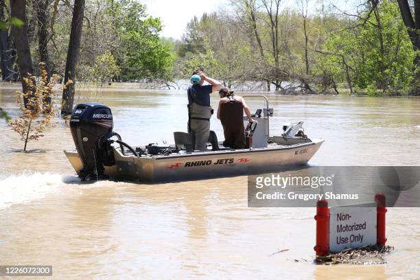 Residents in a boat inspect the floodwaters flowing from the Tittabawassee River into the lower part of downtown on May 20, 2020 in Midland,...