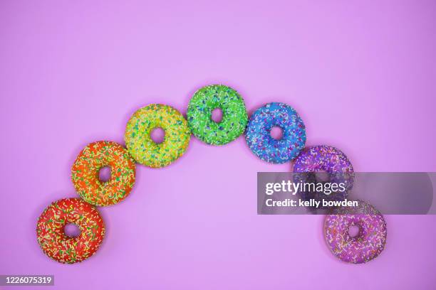 rainbow doughnuts sweets on purple background with copy space - cake flag stock pictures, royalty-free photos & images