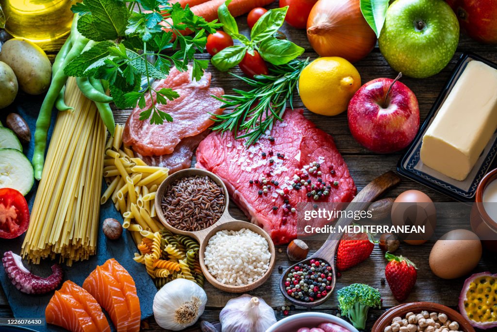Varied food carbohydrates protein vegetables fruits dairy legumes on wood