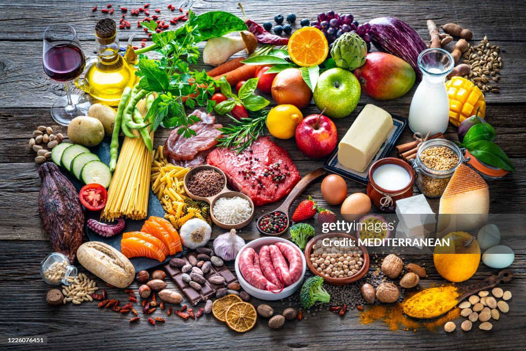 Varied food carbohydrates protein vegetables fruits dairy legumes on wood