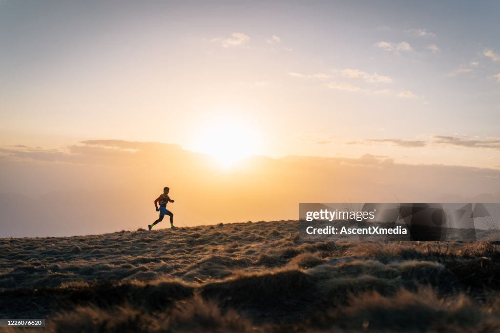 Junger Mann führt bei Sonnenaufgang bergauf