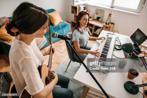 two young female musicians making  a rehearsal in home music studio. - woman in guitar making studio stock pictures, royalty-free photos & images