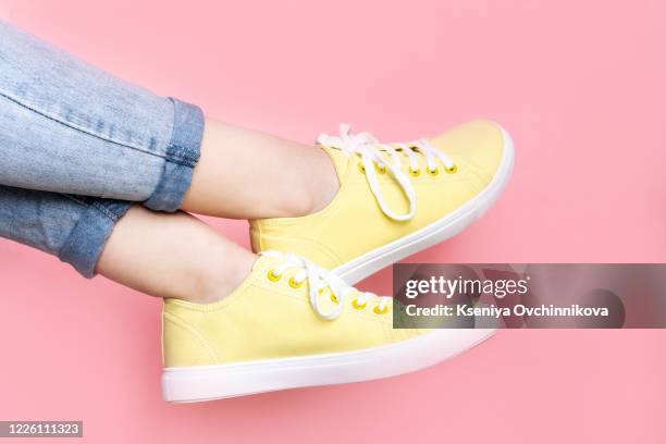 woman in stylish sneakers near color wall, closeup. space for text - zapatos-amarillos fotografías e imágenes de stock