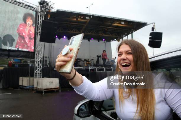 Girl in a car takes a selfie as Casey Donovan performs on stage during a media call to showcase how a drive-in live entertainment venue will operate...