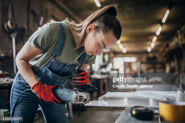 jonge vrouw die met hoekmolen in workshop werkt - slijptol stockfoto's en -beelden