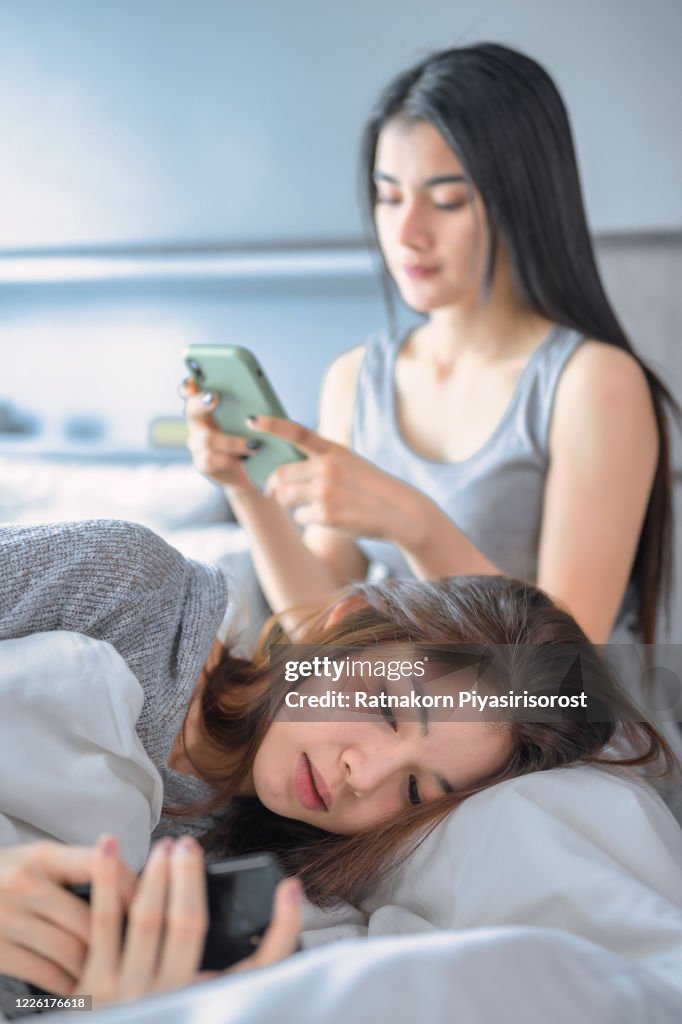 Young Teen Asian Couple having arguments and problems in bed. Asian beauty sad girl was comforted by a girl friend. People and social issues problem concept. Lifestyle and Friendships theme. Lesbian and family theme.