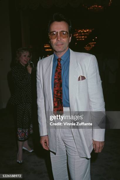 American trumpeter Herb Alpert, co-founder of A&M Records, wearing a white suit with a blue shirt and a red tie, and sunglasses, circa 1985.