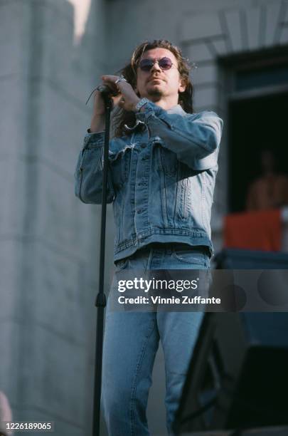 Australian singer-songwriter Michael Hutchence , lead singer with INXS, wearing a denima jacket, jeans and sunglasses, circa 1990.