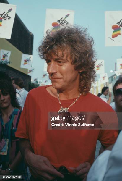 British singer-songwriter Robert Plant wearing a red t-shirt, and a gold chain with a large pendant, backstage during the Live Aid benefit concert,...