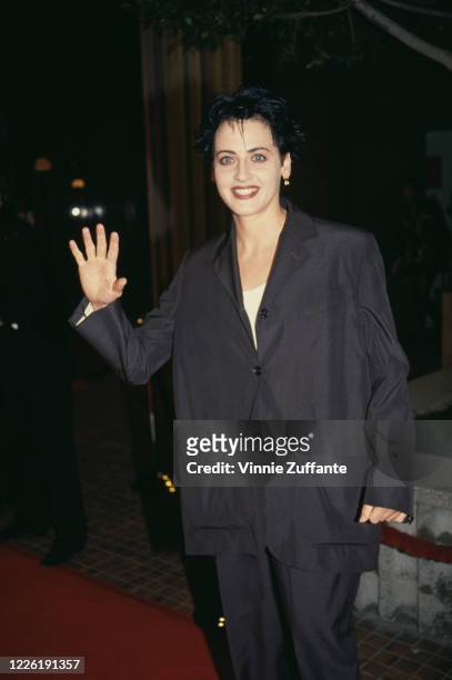 American actress Lori Petty, wearing a black suit, waving as she attends an event, circa 1995.