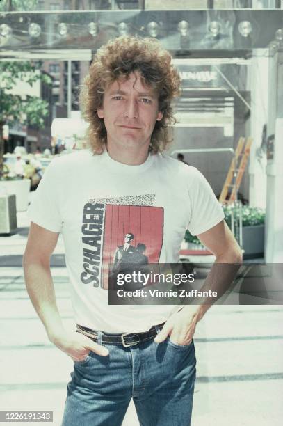 British singer-songwriter Robert Plant poses with his hands in the pockets of his jeans, wearing a white t-shirt with the figure of a man against a...